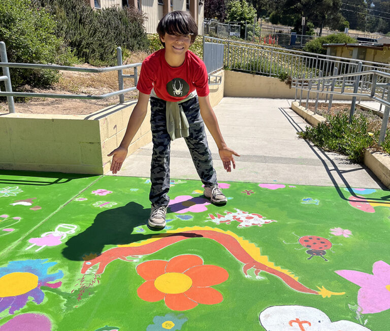 Student stands with mural sharing his contribution